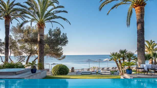 A poolside area with lounge chairs and umbrellas, palm trees, and a view of the sea. - La Villa Mauresque (Saint-Raphaël)