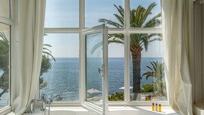 A large bathtub with a view of the sea and palm trees through a large window. - La Villa Mauresque (Saint-Raphaël)