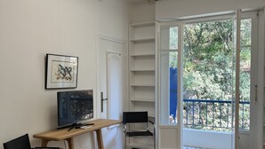 Una sala de estar moderna con piso de madera, un sofá de cuero negro, una silla negra, una mesa de madera con un televisor y un ventilador de techo.