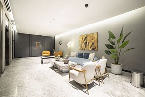 A modern living room with a sofa, armchairs, a coffee table, and a potted plant. - Waves - Impressive 1BR Apartment Close to Burj Khalifa (Dubai)
