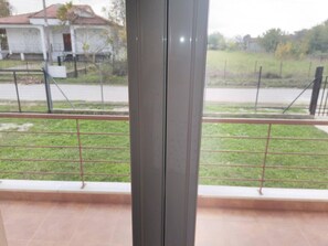 Ein Balkon mit Metallgeländer, Blick auf eine Rasenfläche und ein Gebäude im Hintergrund.