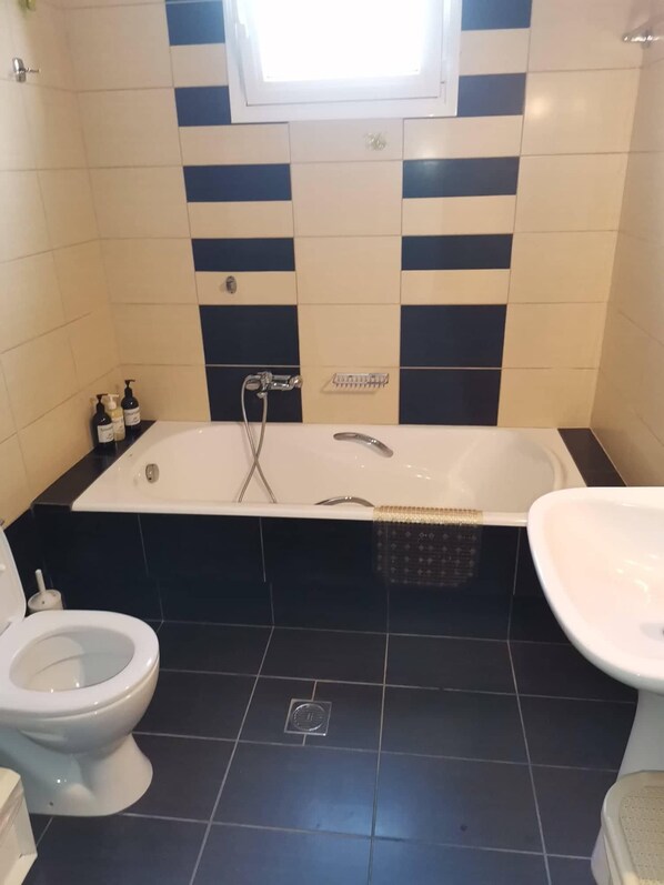 A bathroom with a bathtub, two sinks, and a toilet.