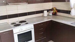Een keuken met donkerbruine kastjes, een witte oven en een betegelde achterwand.