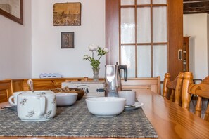 A dining table with a coffee pot, cups, and bowls, a vase with flowers, and a wooden chair. - Colombina House close to @S.Lucia Train Station (Venezia)