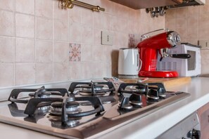 Une cuisine équipée d’une cuisinière à gaz, d’un appareil électroménager rouge et d’un four à micro-ondes blanc.