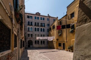A narrow alleyway with buildings on either side, a visible entrance to a building, and clothes hanging on lines. - Colombina House close to @S.Lucia Train Station (Venezia)