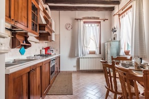 A kitchen with wooden cabinets, a stove, a sink, and a dining area with a table and chairs.