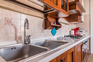 Una cocina con un lavamanos de acero inoxidable doble, una estufa a gas y armarios de madera.