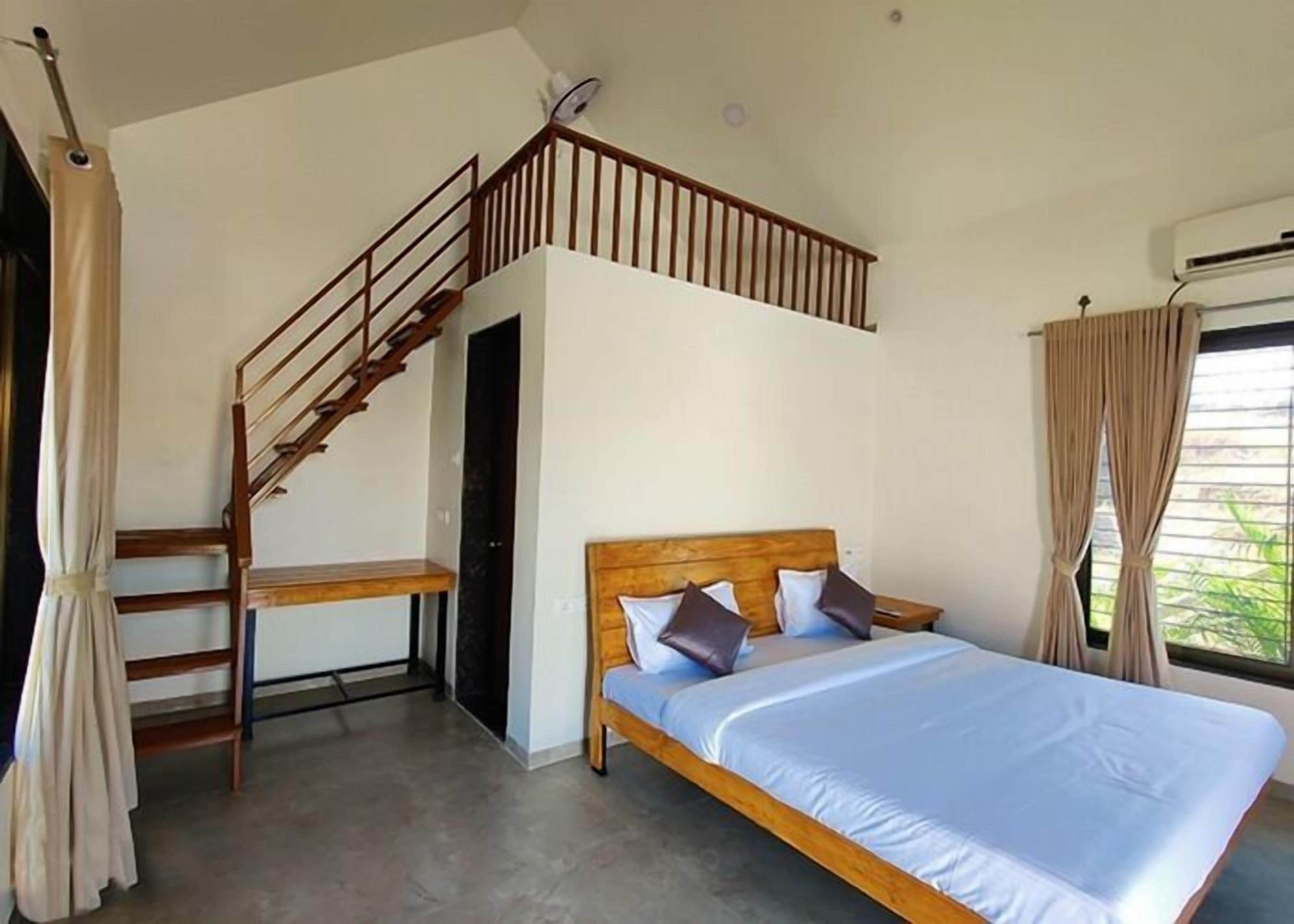 A bedroom with a wooden bed, a staircase, and a window with curtains.