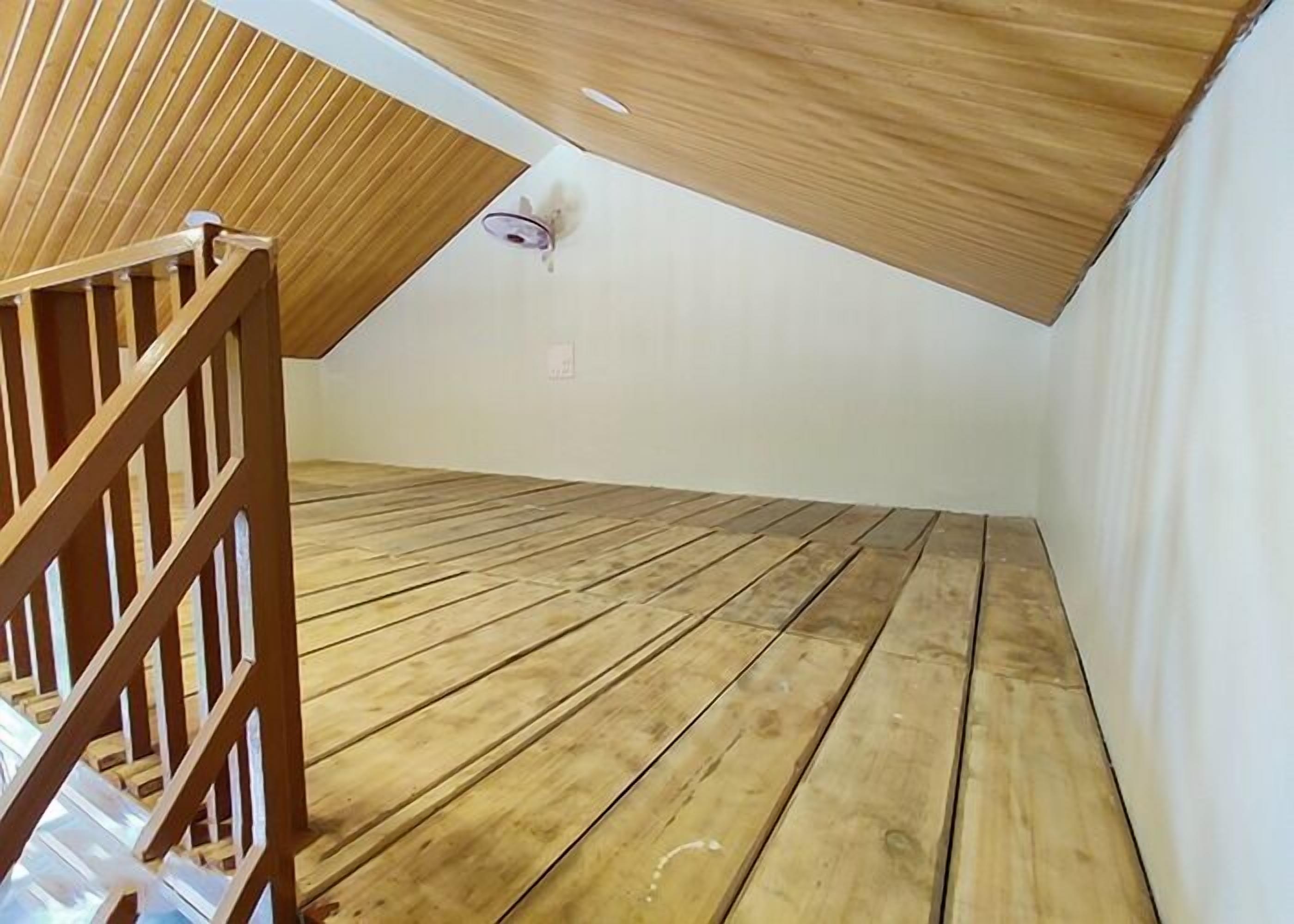 A room with a sloped ceiling and wooden flooring.