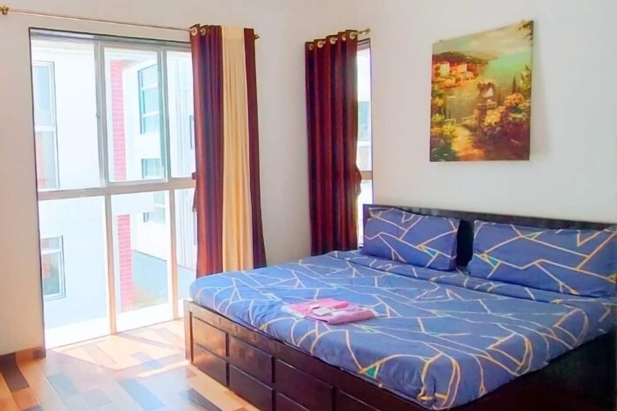 Un dormitorio con una cama, un cuadro y un ventanal corredero.