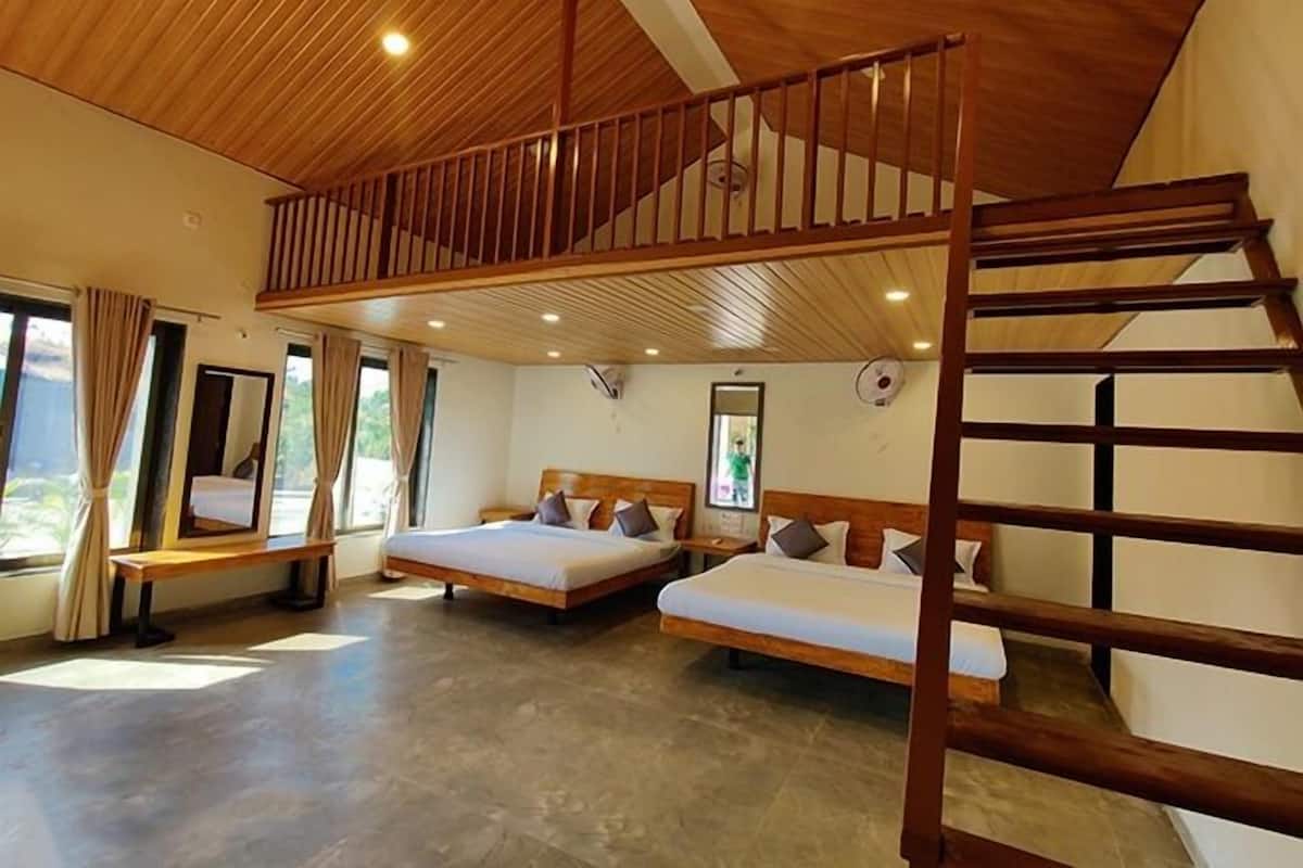 Una habitación con dos camas, techo de madera y un balcón.