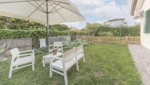 A patio with white furniture, a large umbrella, and a stone wall. - Da Nonna Antonia (Martellago)