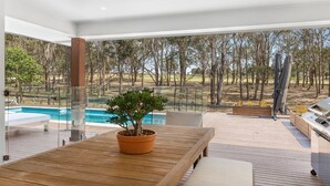 A modern outdoor patio with a wooden table, a potted plant, and a pool. - HUNTER DREAMING - THE VINTAGE HOLIDAY HOUSES (Pokolbin)