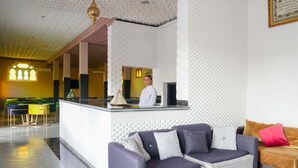 Un hall d’hôtel comprenant un comptoir d’accueil, un canapé et un espace repas.