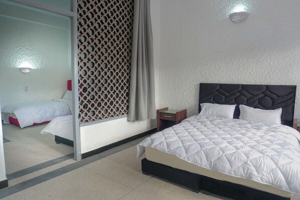 A hotel room with a large bed, a nightstand, a mirror, and a decorative wall panel.