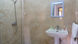 Une salle de bain avec une douche, un lavabo et un miroir.