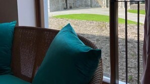 Ein Zimmer mit großem Fenster mit Blick auf ein historisches Steinhaus mit einem Turm.