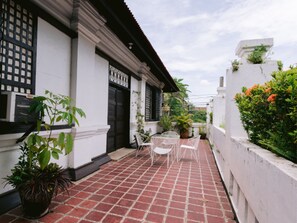 Une maison traditionnelle avec un patio carrelé, des murs blancs et une porte noire.
