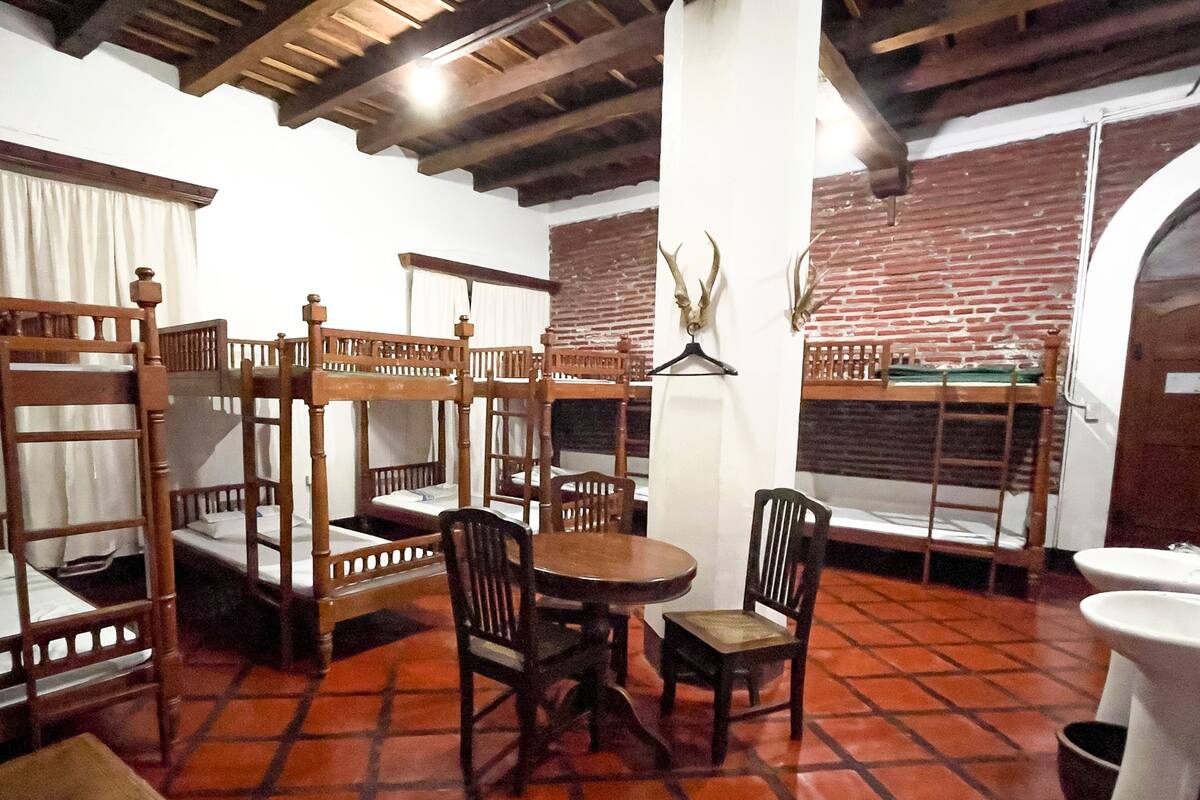 Una habitación con literas, una mesa redonda y sillas.