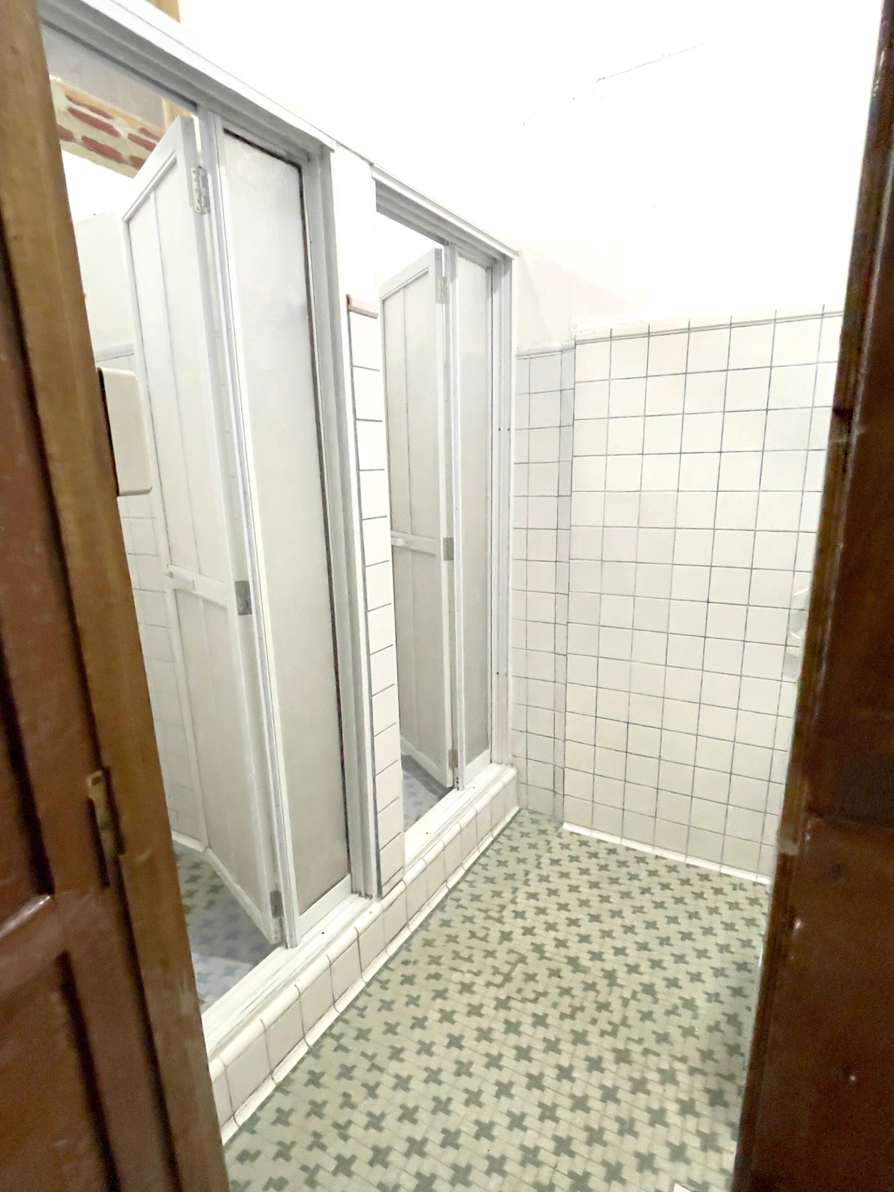 A bathroom with a shower, tiled walls, and a patterned floor.