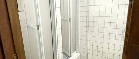 A bathroom with a shower, tiled walls, and a patterned floor.