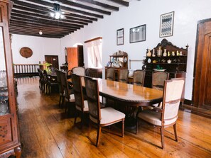 Un coin repas avec une table et des chaises en bois, un lustre et une étagère ornée d’objets décoratifs.