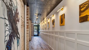 A hallway with a brick wall, wooden floor, and artwork on the walls. - New Construction Loft Style Spacious Lux Apt 201 (Atlanta)