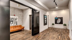 A modern interior with a wooden floor, a black door, and a brown leather sofa. - New Construction Loft Style Spacious Lux Apt 201 (Atlanta)