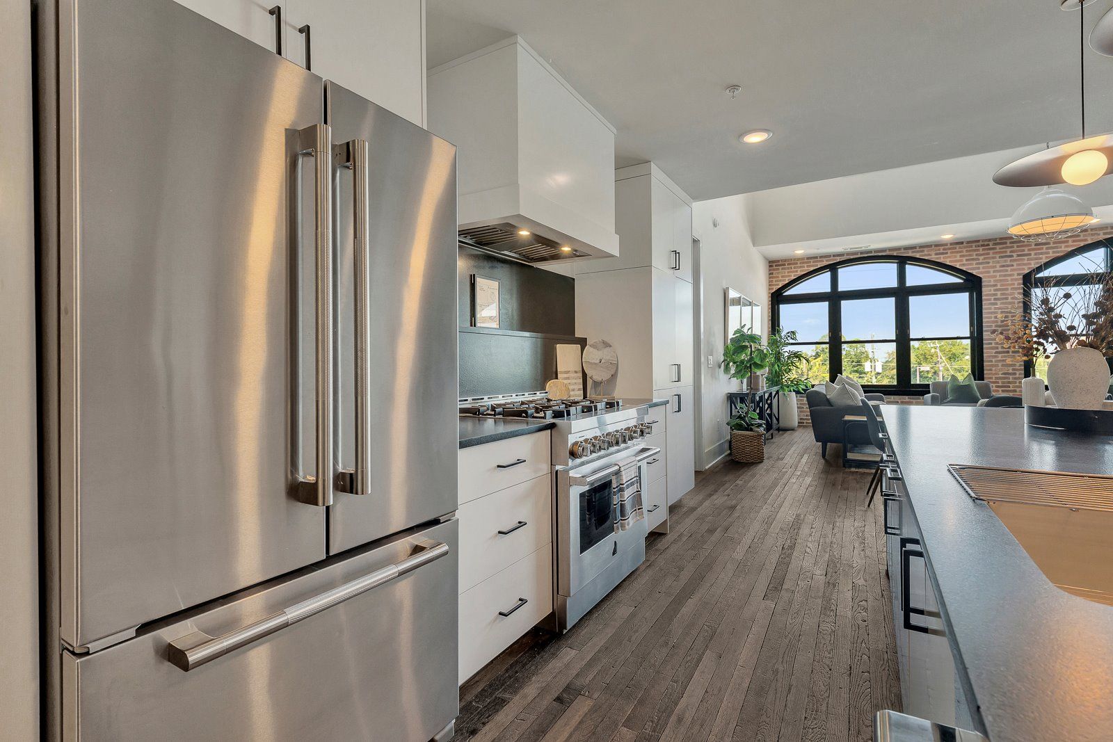 A modern kitchen with stainless steel appliances, a large window, and a dining area with a view.