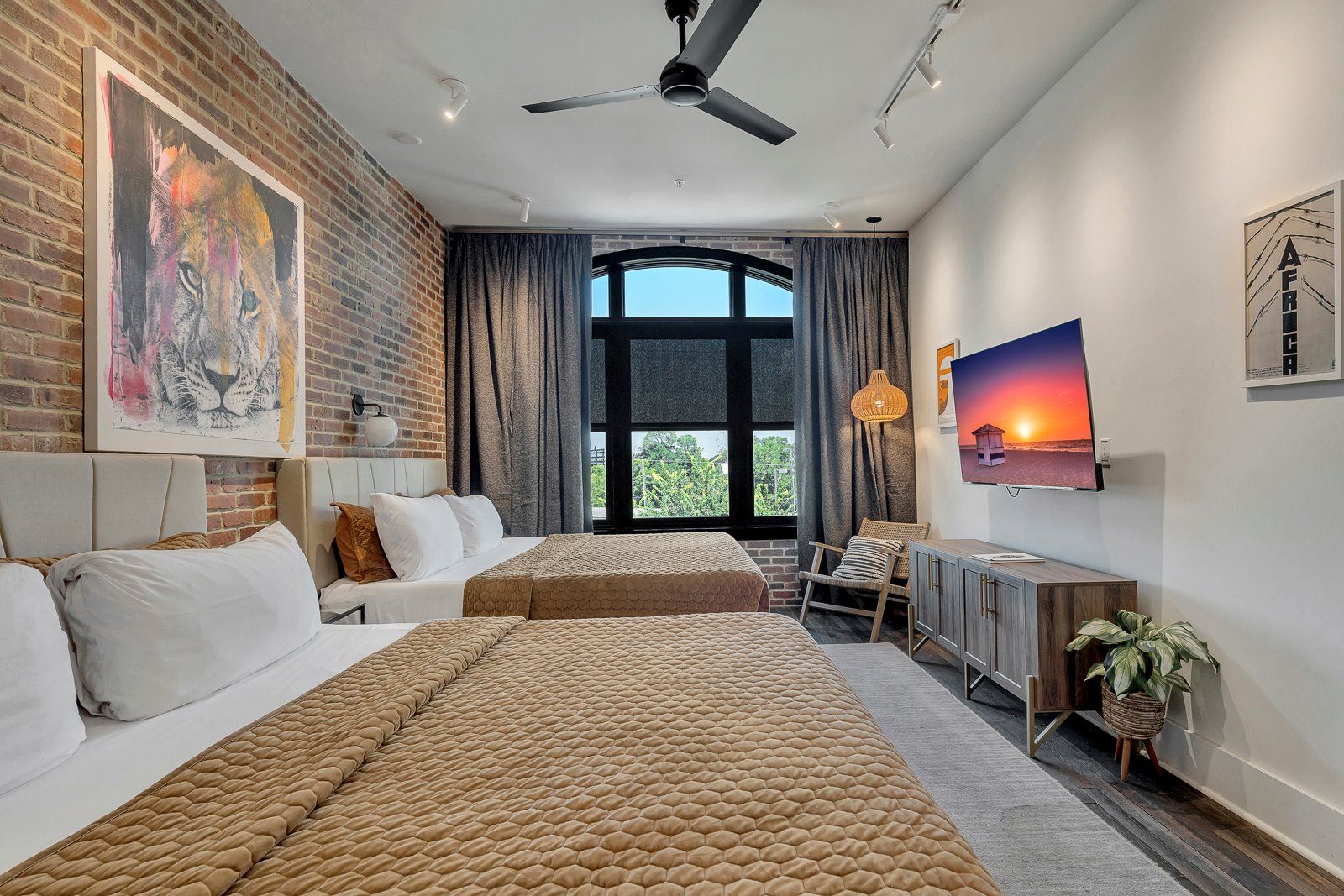 A modern hotel room with a large bed, a desk, a chair, and a TV.