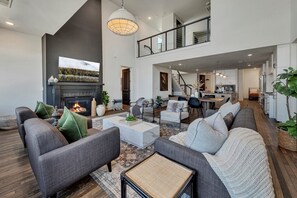 A spacious living area with a fireplace, sofas, a coffee table, and a kitchen in the background. - Benz View Penthouse w Rooftop, Secure Parking (Atlanta)