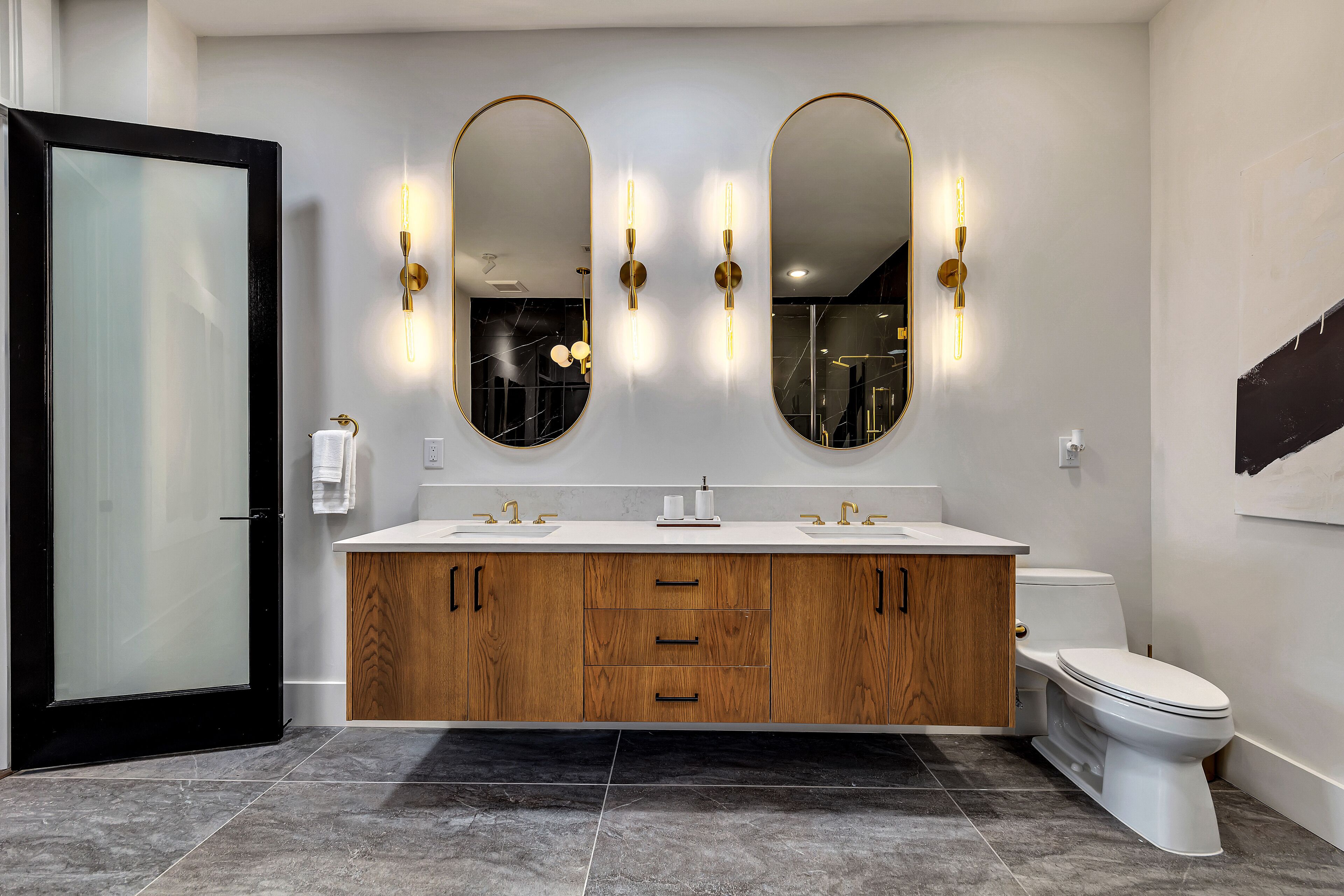 Une salle de bain moderne avec un meuble-lavabo double, des armoires en bois et des toilettes blanches.
