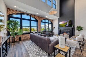 A modern living room with a fireplace, large windows, and a cozy seating area. - Benz View Penthouse w Rooftop, Secure Parking (Atlanta)