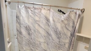 Un baño con cortina de ducha de mármol, un inodoro y un armario.