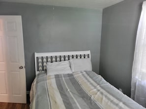 A bedroom with a bed, a door, and a window with curtains. - Spencerville Center House (Tallahassee)