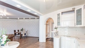 Une cuisine moderne avec des meubles blancs, un réfrigérateur et un coin repas comprenant une table et des chaises.