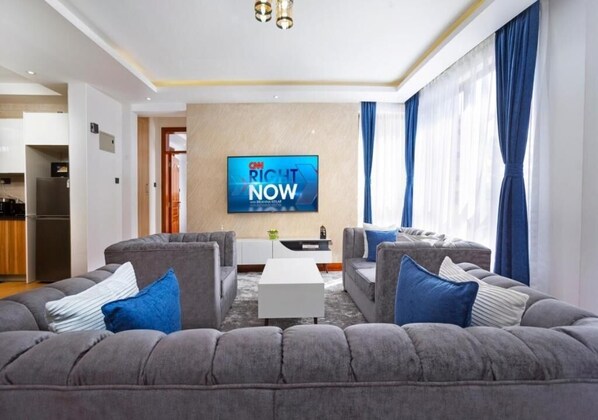 A modern living room with a grey sectional sofa, a flat-screen TV, and a small coffee table.