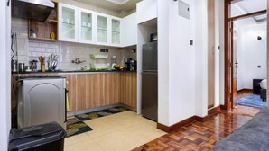 Eine kleine Küche mit einem Kühlschrank, einer Mikrowelle und Holzausstattung.
