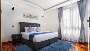 Ein modernes Schlafzimmer mit einem großen Bett, einem Nachttisch und einem blauen Teppich.