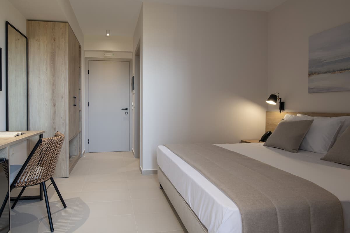 A bedroom with a bed, bedside table, lamp, and a chair.