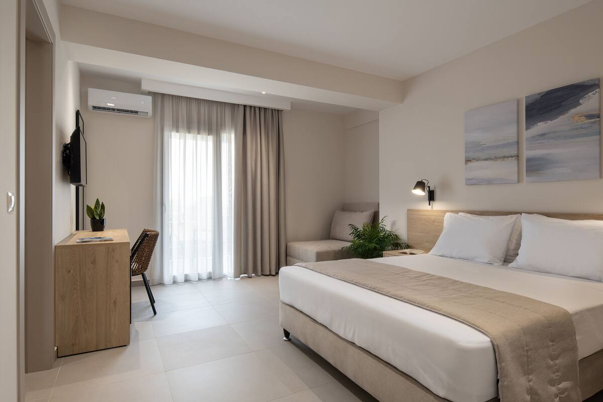 A modern hotel room with a large bed, a desk, and a chair.