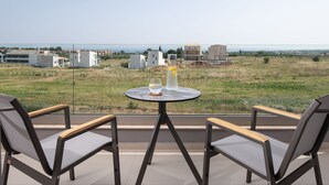 A balcony with two chairs and a table, overlooking a grassy field and buildings. - Calives Premium Stay (Polygyros)
