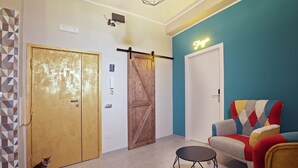 Een kamer met een schuifdeur van hout, een neonbord, een gestreept bankstel en een kat.