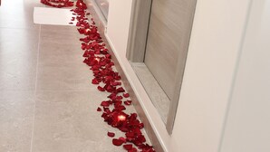 Een hal met een roodgekleurd tapijt en rozenblaadjes die naar een badkamer leiden.