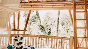 A room with a bed, a ladder, and a view of trees. - La Royale Nusa Penida (Penida Island)