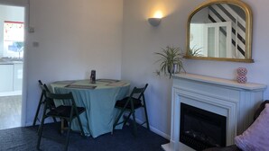 A dining area with a round table, four chairs, a fireplace, and a mirror with a striped frame. - Comfy modern townhouse/w free parking & garden, newly refurbished, self catering (Cheltenham)