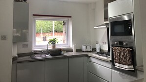A modern kitchen with a built-in oven, microwave, and gas stove. - Comfy modern townhouse/w free parking & garden, newly refurbished, self catering (Cheltenham)