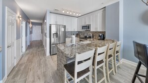 A modern kitchen with white cabinets, stainless steel appliances, and a granite countertop.