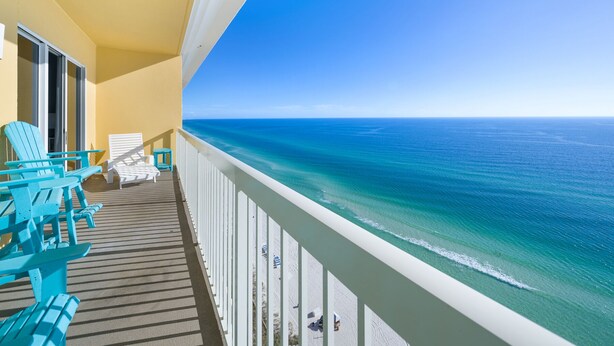 A balcony with turquoise chairs and a view of the ocean.